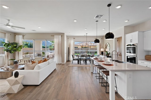 interior space with visible vents, open floor plan, light countertops, double oven, and a sink