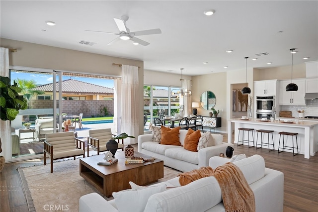 living room with recessed lighting, visible vents, and wood finished floors