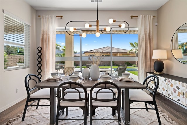 dining room with an inviting chandelier, visible vents, baseboards, and wood finished floors