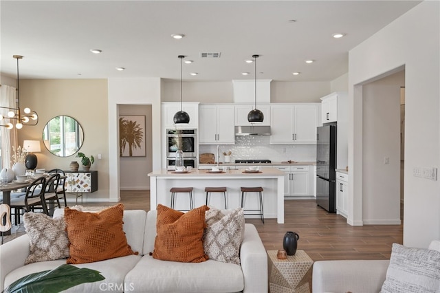 living room with dark wood finished floors, visible vents, a notable chandelier, and recessed lighting