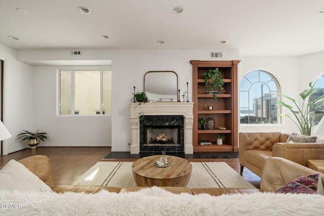 living room with a premium fireplace, visible vents, recessed lighting, and wood finished floors