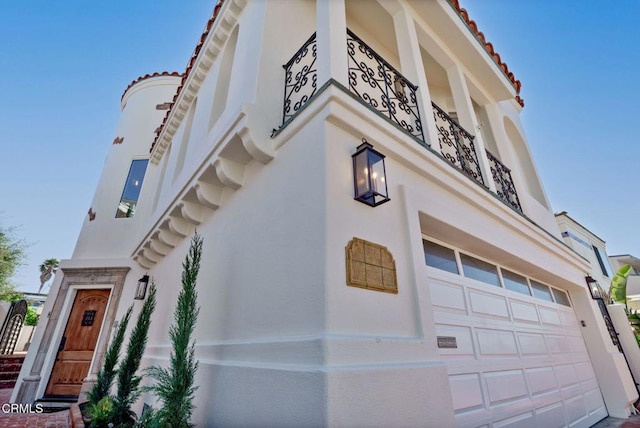 view of front of house featuring stucco siding, a garage, and a tile roof