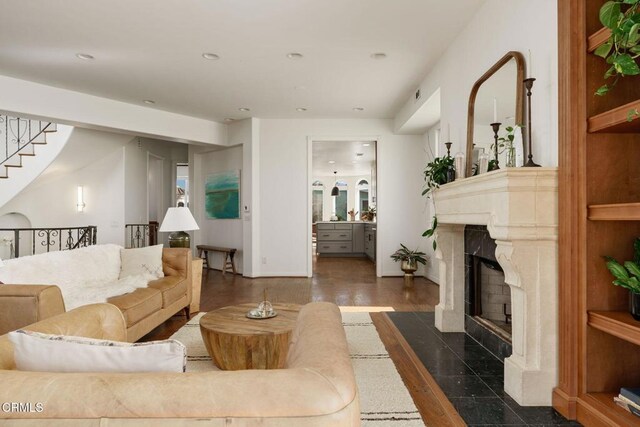 living area featuring stairway, wood finished floors, baseboards, recessed lighting, and a fireplace