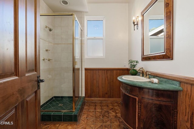 bathroom with wooden walls, wainscoting, a stall shower, and vanity
