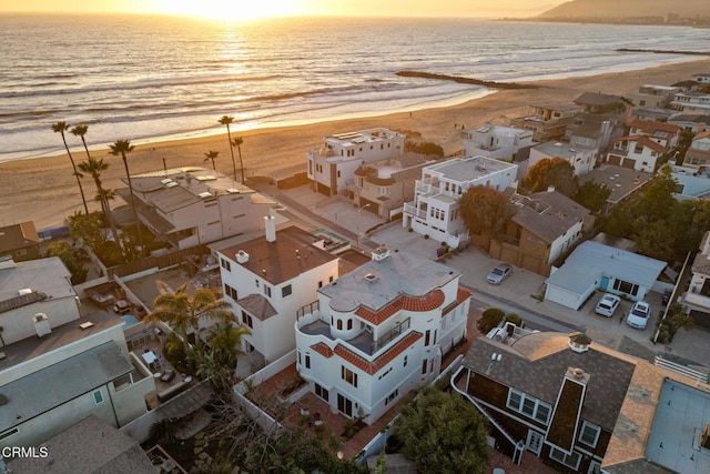 aerial view at dusk featuring a beach view and a water view