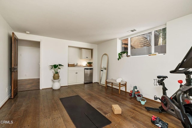 workout room with a sink, visible vents, baseboards, and dark wood finished floors