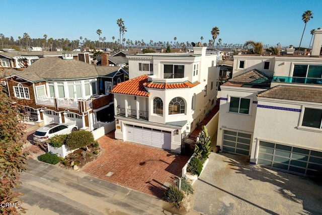 view of front facade featuring an attached garage, a residential view, driveway, and stucco siding