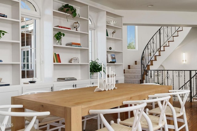 dining room featuring stairs, a healthy amount of sunlight, and dark wood-style flooring
