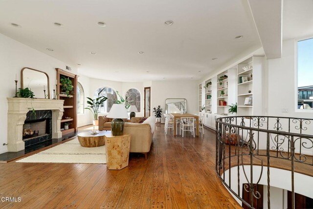 living area featuring recessed lighting, a fireplace, visible vents, and wood-type flooring