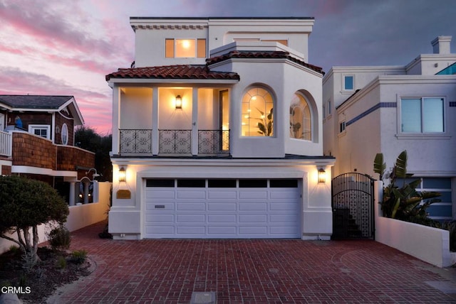 mediterranean / spanish house with stucco siding, decorative driveway, a garage, and a gate