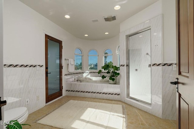full bathroom with tile patterned floors, visible vents, toilet, tile walls, and a shower stall