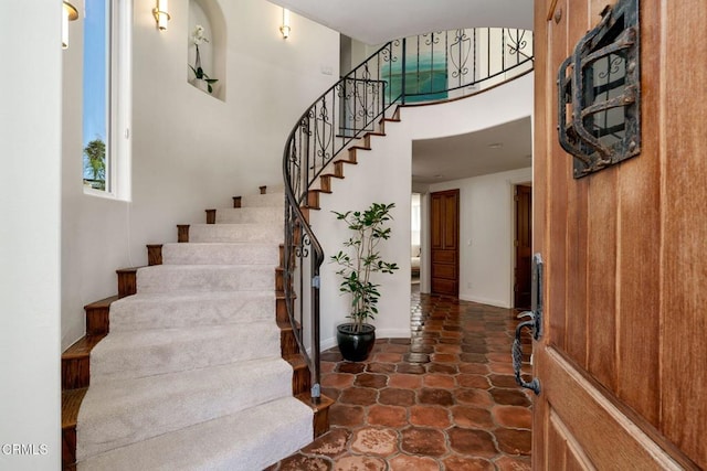 entrance foyer featuring baseboards, a high ceiling, and stairs