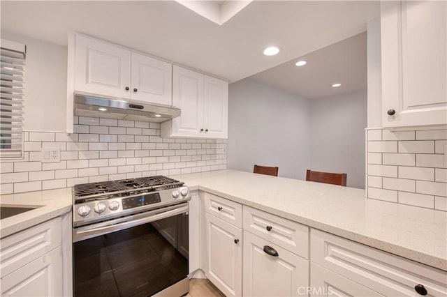 kitchen featuring under cabinet range hood, tasteful backsplash, white cabinetry, gas stove, and light stone countertops