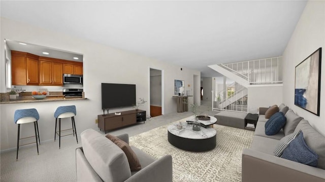 living room featuring recessed lighting, light carpet, and stairs