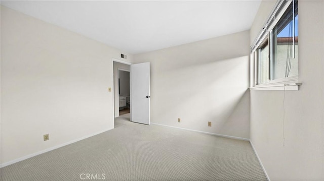 carpeted spare room featuring baseboards and visible vents