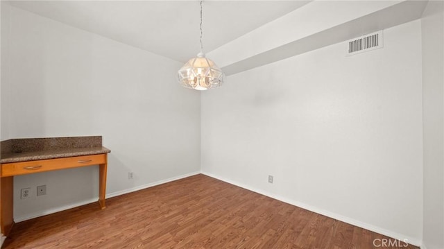 empty room featuring visible vents, baseboards, and wood finished floors