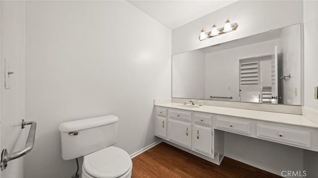 bathroom featuring vanity, wood finished floors, toilet, and baseboards