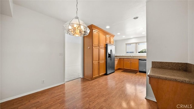 kitchen with recessed lighting, a sink, fridge with ice dispenser, stainless steel dishwasher, and light wood finished floors