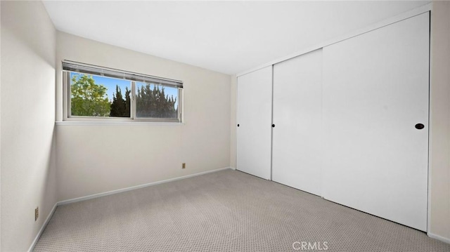 unfurnished bedroom with carpet floors, a closet, and baseboards