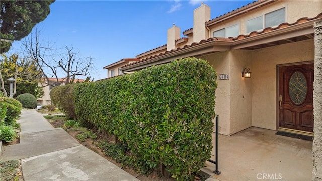 doorway to property with a chimney and stucco siding