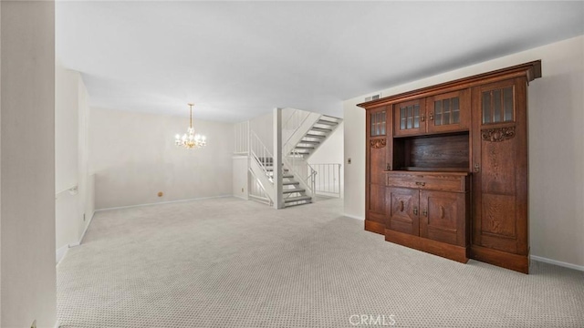 unfurnished living room with carpet floors, a chandelier, stairway, and baseboards