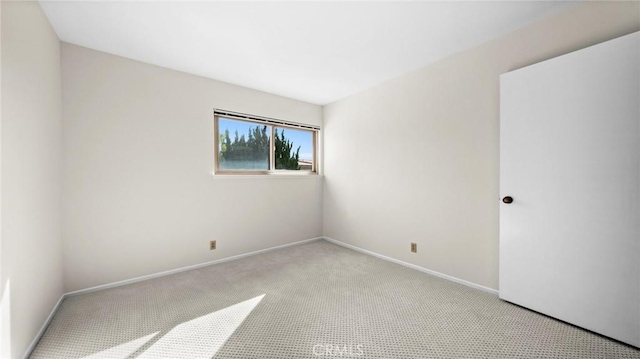 carpeted spare room featuring baseboards