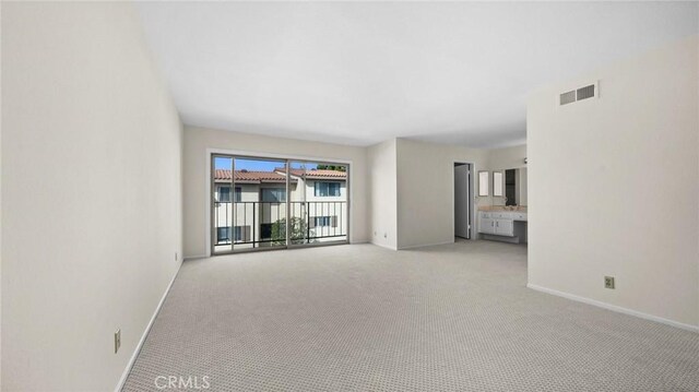 empty room with visible vents, light carpet, and baseboards