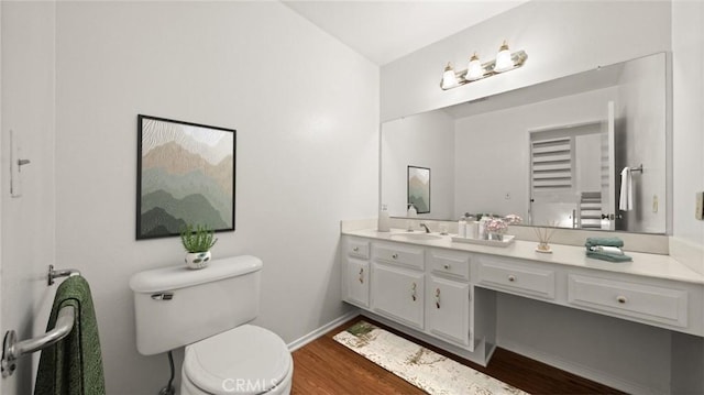 bathroom with toilet, baseboards, wood finished floors, and vanity