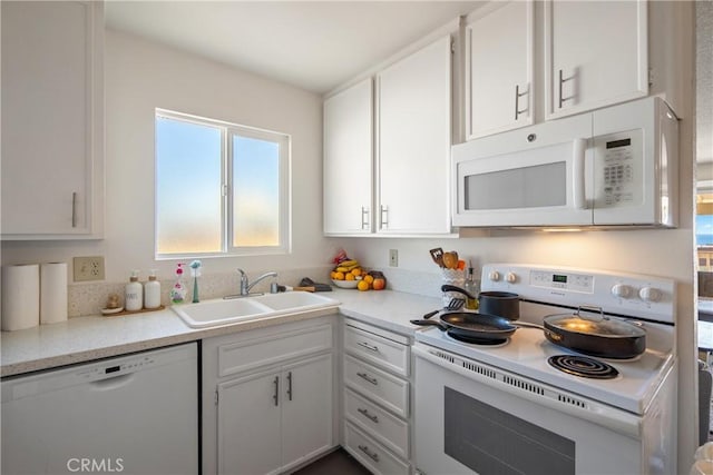 kitchen featuring white appliances, light countertops, a sink, and white cabinetry