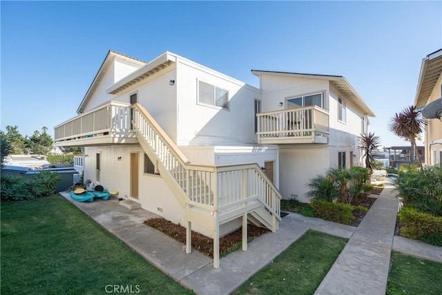 back of property with stairs and a lawn