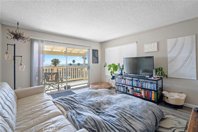 bedroom featuring access to outside, a textured ceiling, and wood finished floors