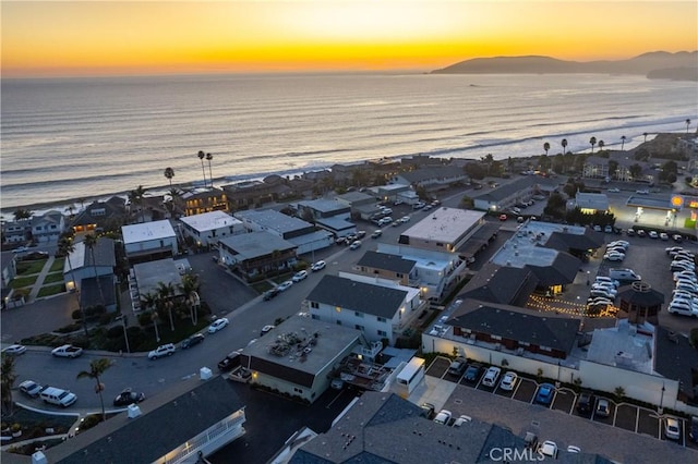 aerial view at dusk featuring a view of the beach and a water view