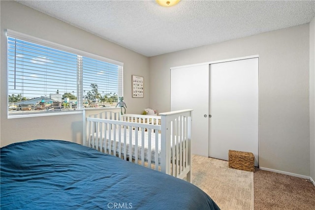 bedroom with a textured ceiling, a closet, multiple windows, and carpet flooring