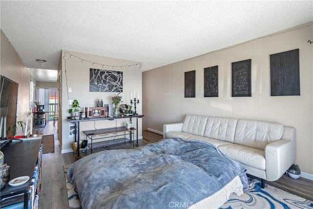 bedroom featuring a textured ceiling, baseboards, and wood finished floors