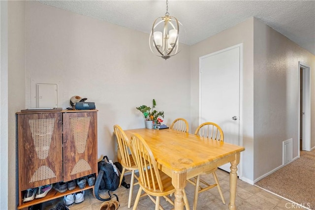 dining space with visible vents, a chandelier, and a textured ceiling