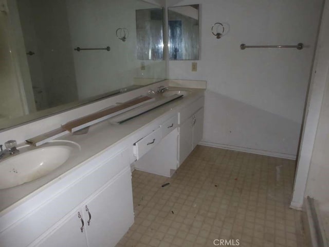 full bath with baseboards, double vanity, a sink, and tile patterned floors