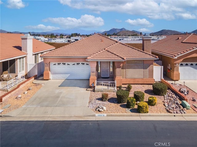 view of front of property featuring an attached garage, a mountain view, a tile roof, concrete driveway, and stucco siding