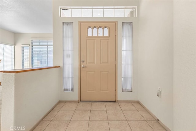 entrance foyer with light tile patterned floors and baseboards