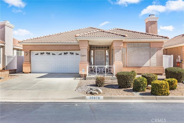 view of front of house with a garage, fence, concrete driveway, a tiled roof, and stucco siding