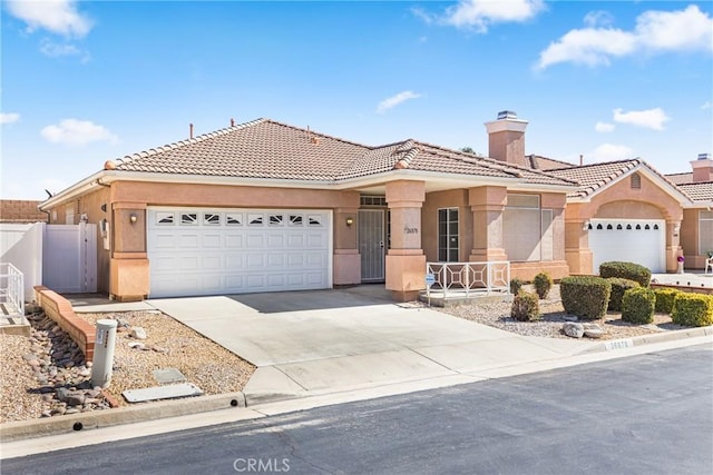 view of front of property with driveway, fence, an attached garage, and stucco siding