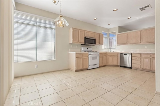 kitchen featuring stainless steel appliances, light brown cabinetry, a sink, and visible vents