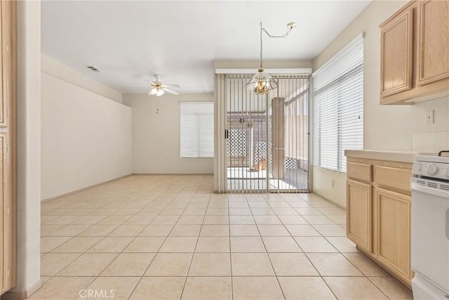 kitchen featuring light tile patterned floors, tile countertops, white electric range, light brown cabinets, and ceiling fan with notable chandelier