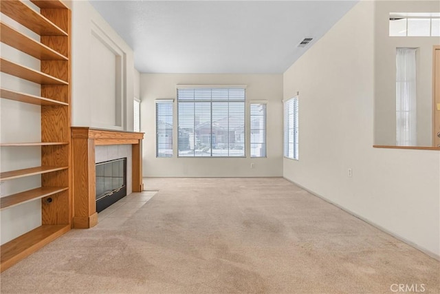 unfurnished living room with carpet floors, visible vents, and a tiled fireplace