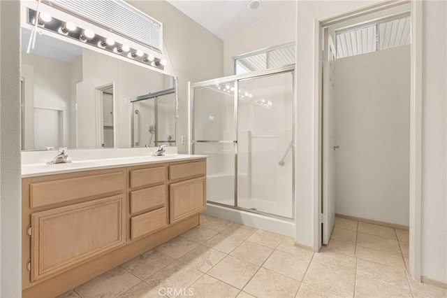 full bath featuring a sink, double vanity, a stall shower, and tile patterned flooring