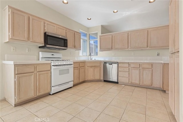 kitchen featuring stainless steel appliances, tile counters, light tile patterned flooring, and light brown cabinetry