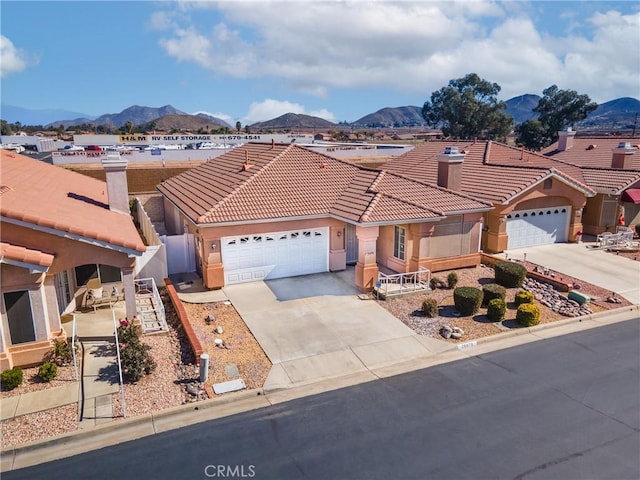 view of front of property with driveway, an attached garage, a tile roof, and a mountain view