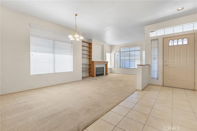 entrance foyer featuring a fireplace, light tile patterned floors, an inviting chandelier, light carpet, and baseboards