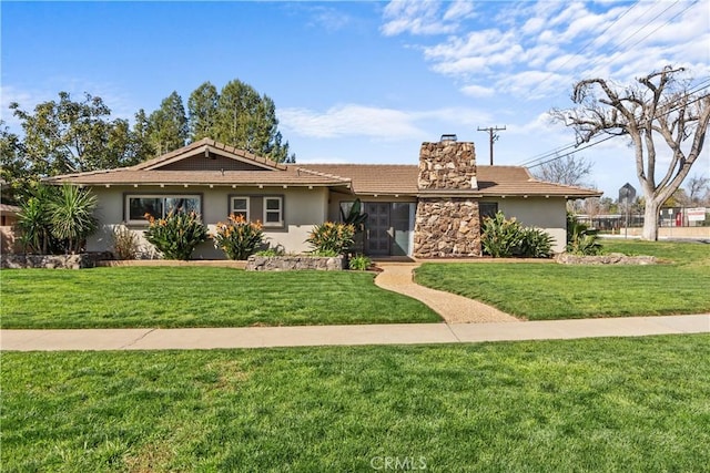 ranch-style home featuring stucco siding, a front yard, and a chimney