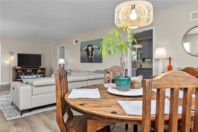 dining area with visible vents, light wood-style floors, and a notable chandelier