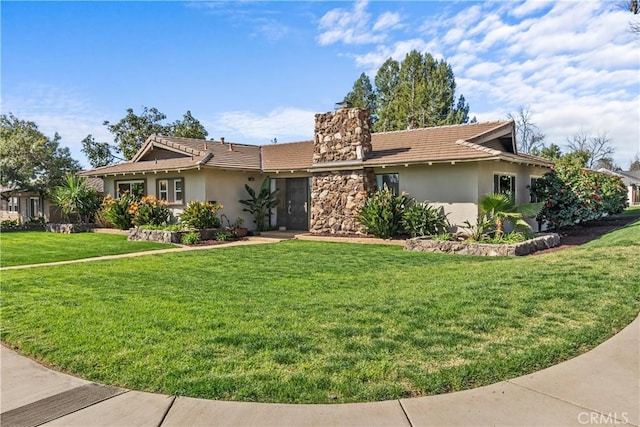 view of front of house featuring a tiled roof, a front yard, stucco siding, a chimney, and stone siding